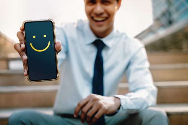 man holding phone which show smile emoji