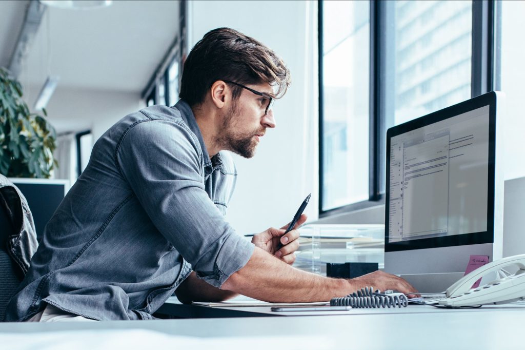 man working on computer at desk in office