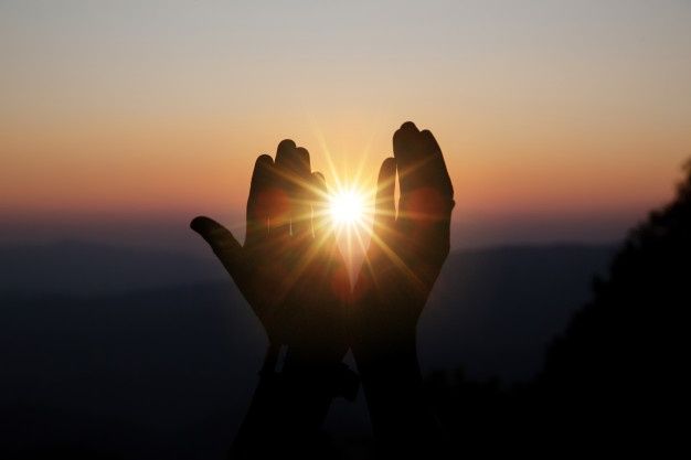 Spiritual prayer hands over sun shine with blurred beautiful sunset
