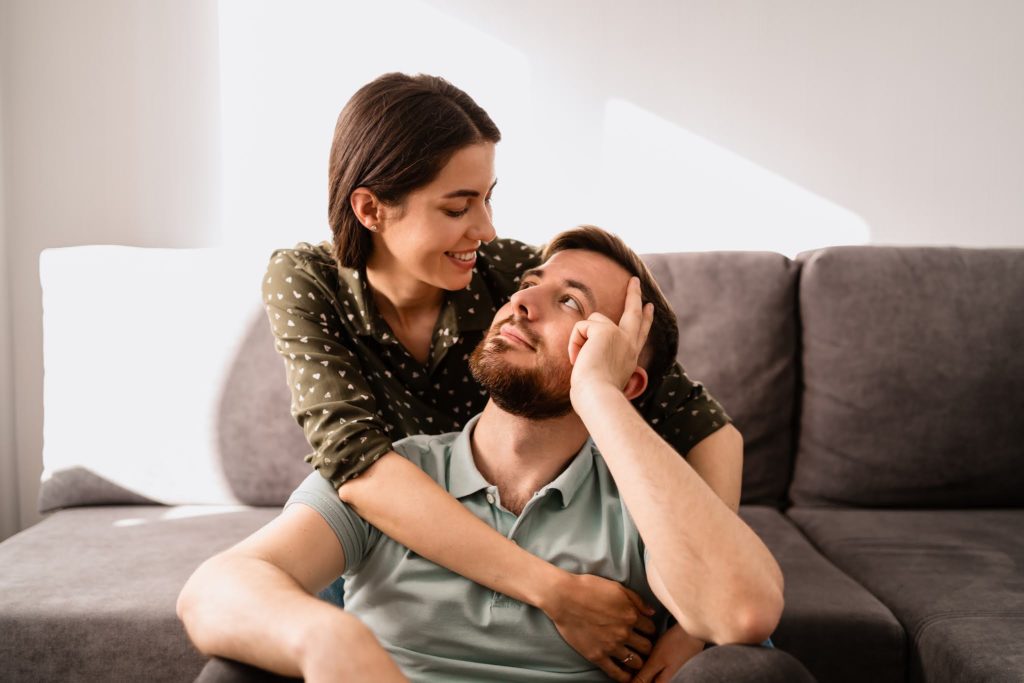 Man and woman portrait smiling to each other on the sofa