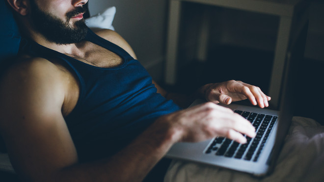 man using laptop on bed