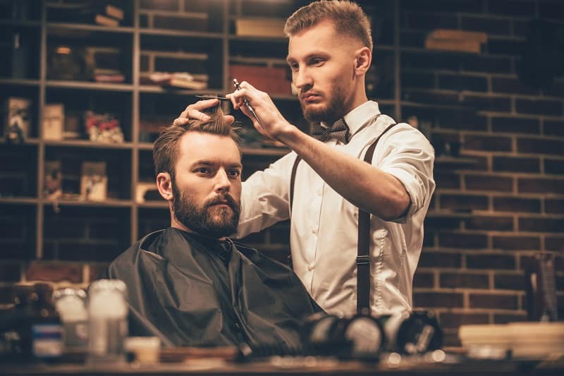 man trimming hair at barber shop