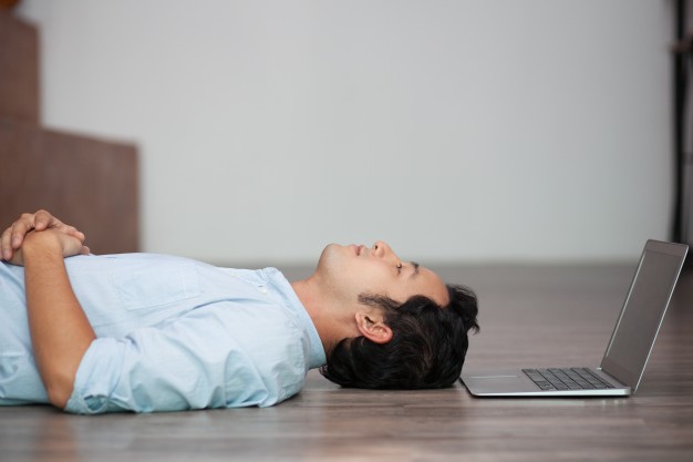 man lying on floor at his laptop