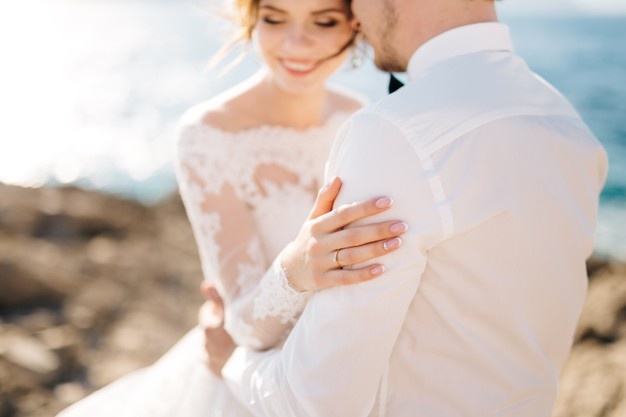 Bride and groom are hugging on the rocky beach of the mamula island