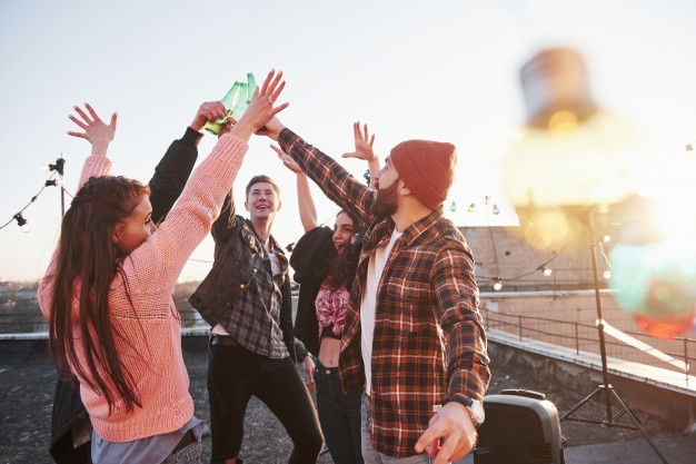 cheerful group of friends raised their hands up with alcohol 