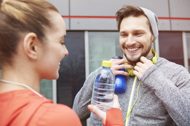 Happy couple drinking water after exercise 