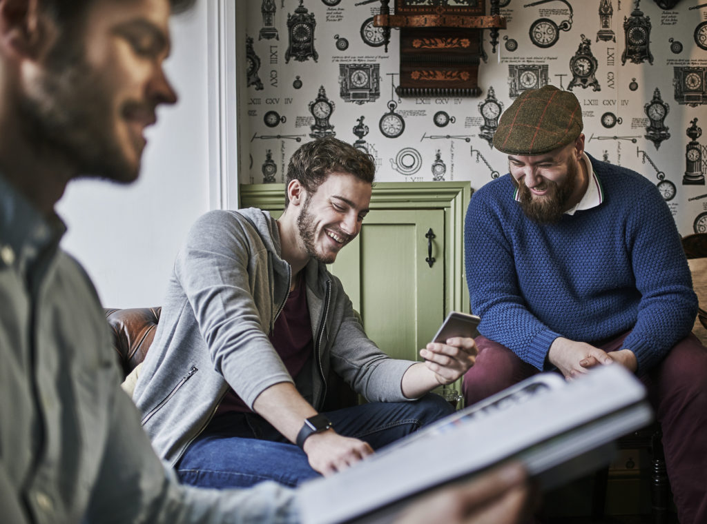 Men looking at smart phone and laughing together