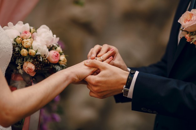 groom putting ring on bride's finger
