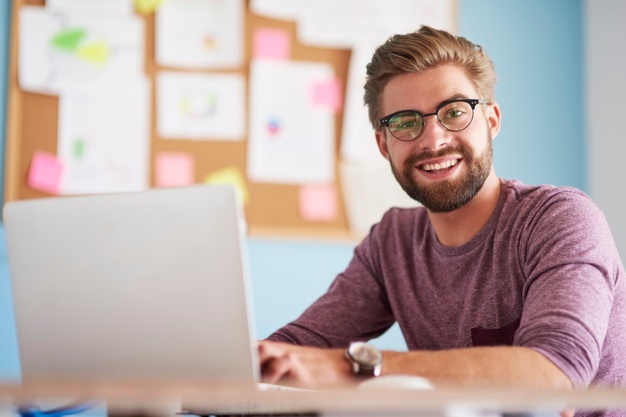 Happy man with laptop computer at office