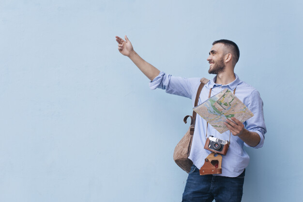 Young traveler man showing something with holding map standing against blue background