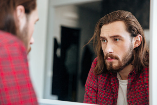 man looking up himself in mirror