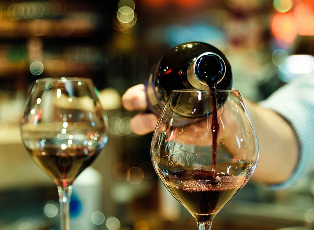 man pouring wine into glasses