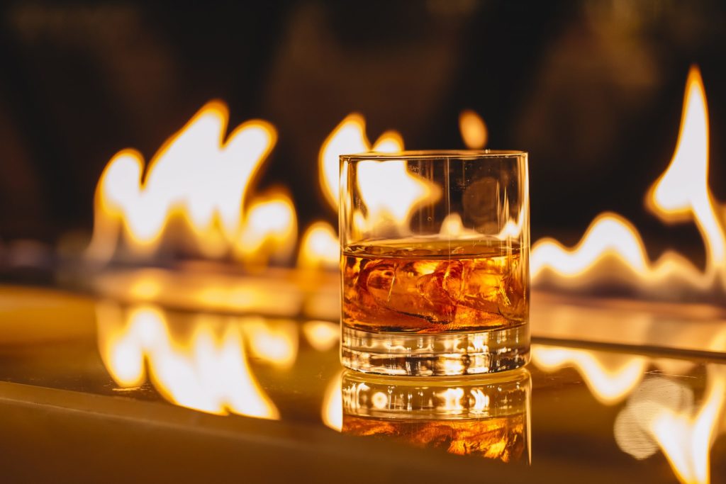 glass of whiskey with ice on a background of a burning flame