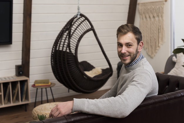Side view of man posing on sofa at home