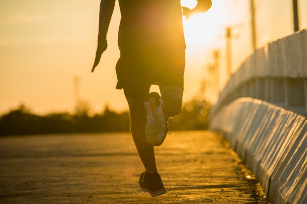 Silhouette of a young fitness man running on sunrise