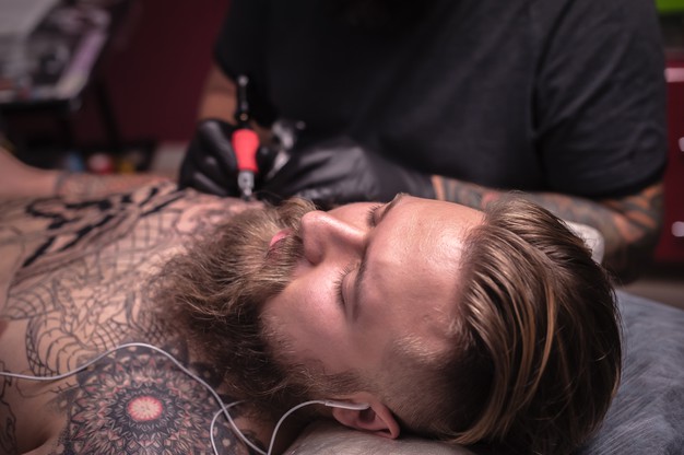 Professional tattooer demonstrates the process of getting tattoo in his salon