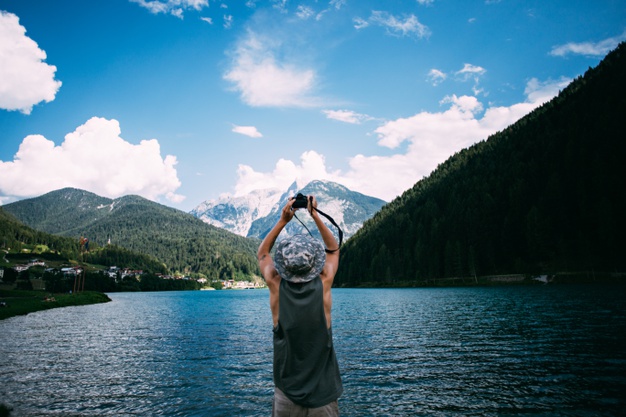 Tourist taking photos of nature landscape using his smartphone 