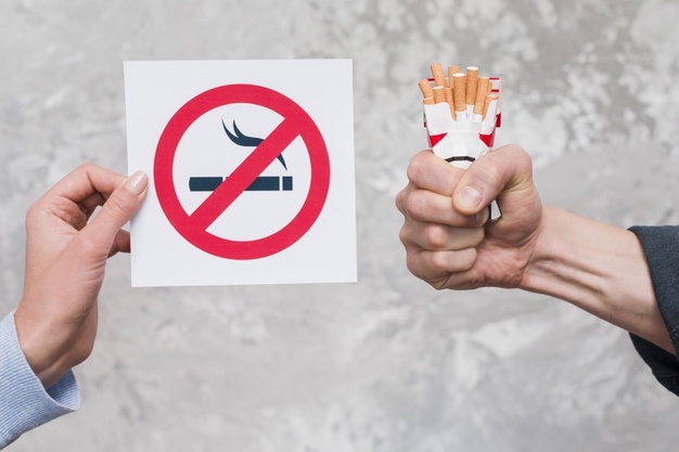 woman-s-hand-holding-no-smoking-sign-near-man-s-hand-holding-packet-cigarettes