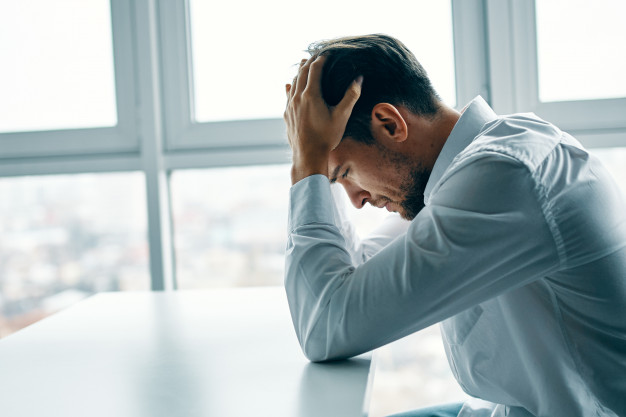 young-man-sitting-table-depressed-against-window