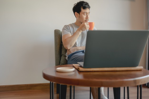 man is working with his laptop and drinking coffee