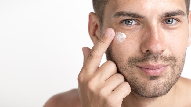 young stubble man applying cream on her face