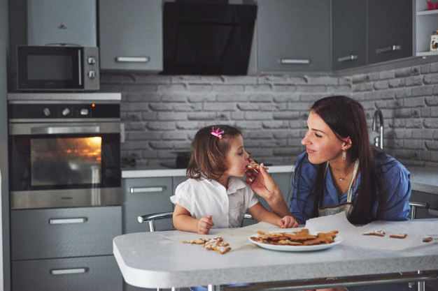 mother and daughter decorate cookies. happy family in making homemade pastry. 