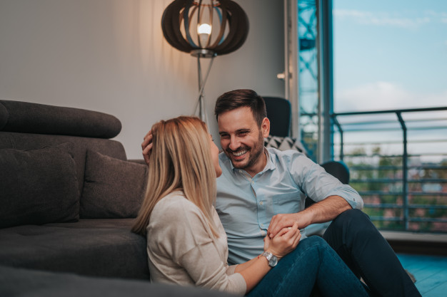 Laughing couple sitting on the floor at home. enjoy spending time together