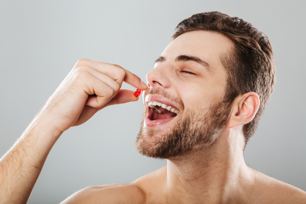 a happy man taking a red capsule 