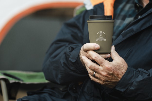 Senior man holding green reusable cup 