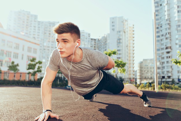 Tense handsome guy with a good body at workout in the morning on stadium