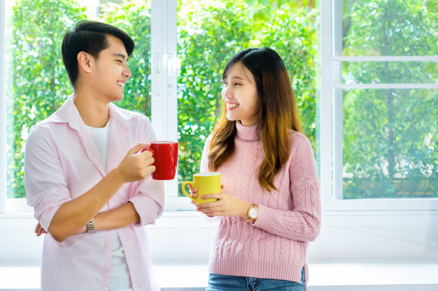 Young couple talking and drink beverage at home 