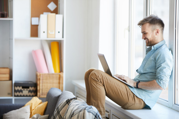 Young man using laptop by window 