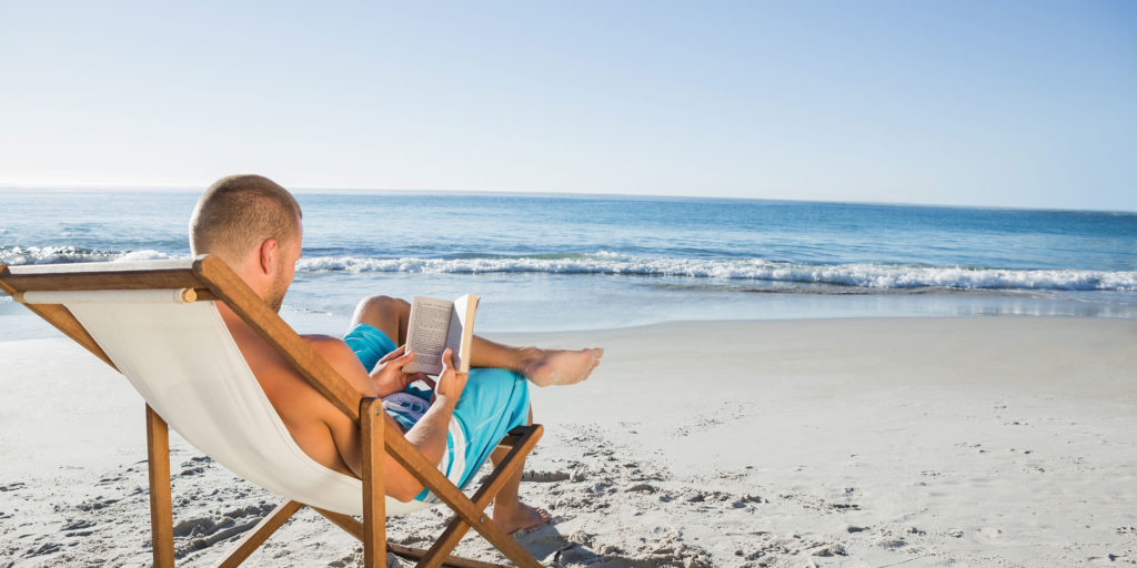 man reading a book on the beach