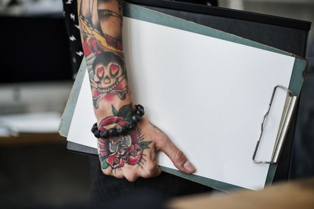 Arm with tattoo carrying clipboard 