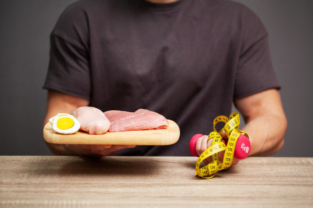 man holding a board with meat for proper nutrition of the athlete