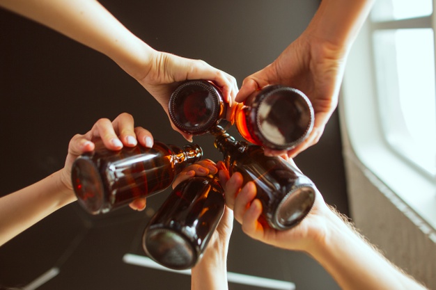 young group of friends drinking beer, having fun, laughing and celebrating together
