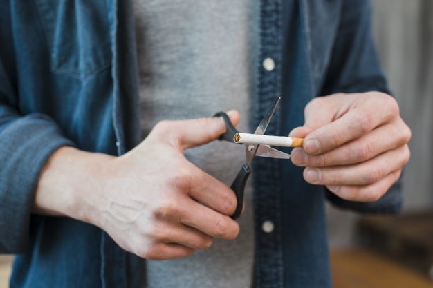 close-up-man-s-hand-cutting-cigarette-with-scissor