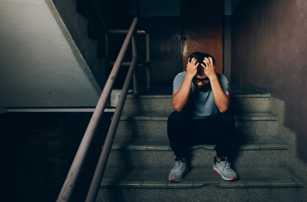 depressed-man-sitting-stairs-building-holding-his-forehead-while-having-headache