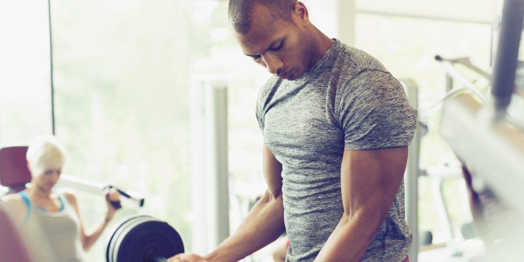 focused-man-doing-barbell-biceps-curls-at-gym