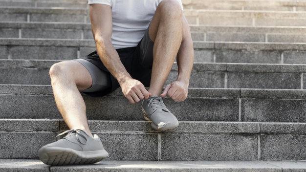 man tying her shoelaces before exercising 