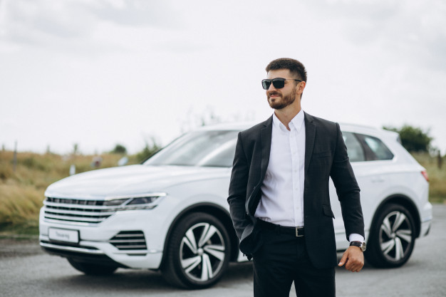 Handsome business man by the white car 