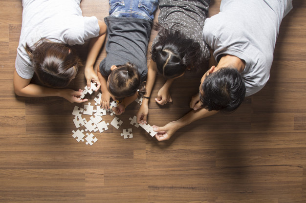 Happy family top view lying on floor with solving a jigsaw puzzle