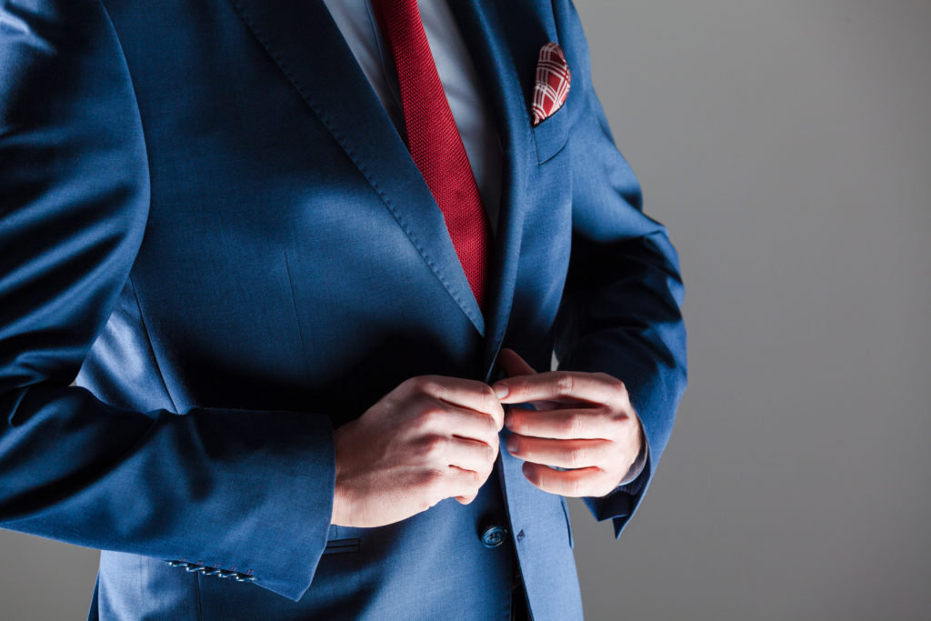 Close up of elegant businessman wearing navy blue jacket, red tie and pocket square