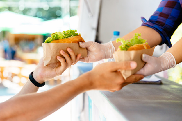 man-buying-two-hot-dog-kiosk-outdoors-street-food-close-up-view