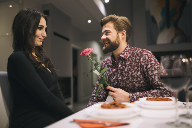 Man giving rose to girl in cafe 