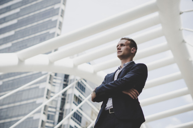 Portrait of happy businessman standing on front of business center