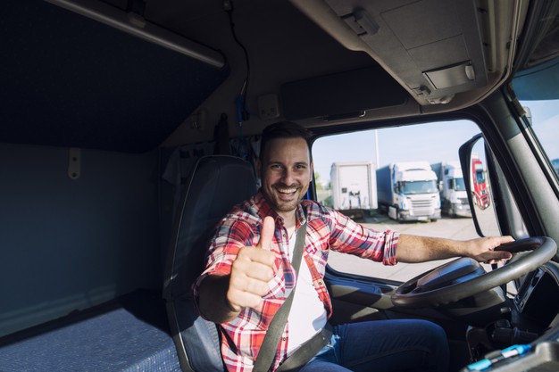 motivated truck driver holding thumbs up in truck cabin
