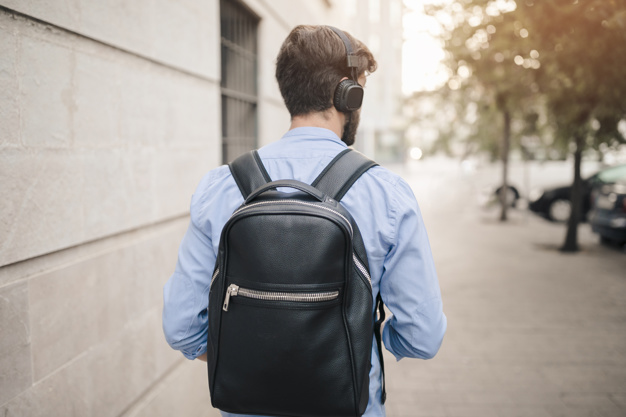 a man with backpack walking on pavement 