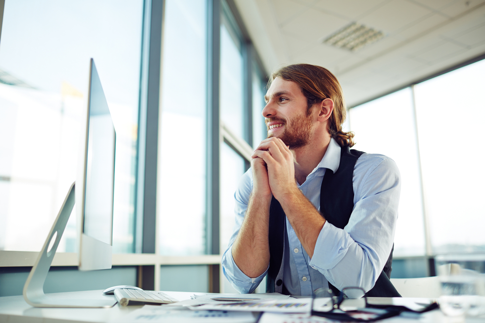 Cheerful businessman siting by desk in office