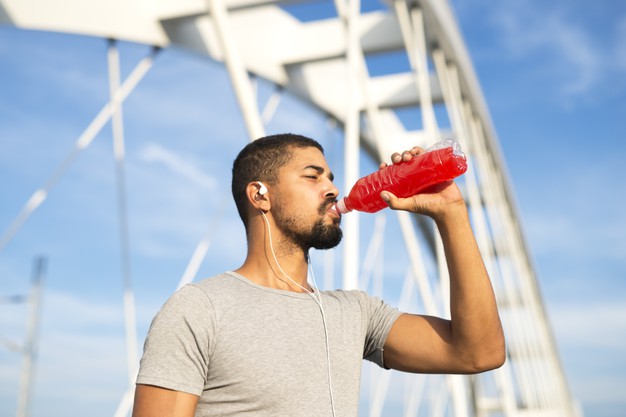 Sportsman drinking refreshing energy drink after training hydrating his body